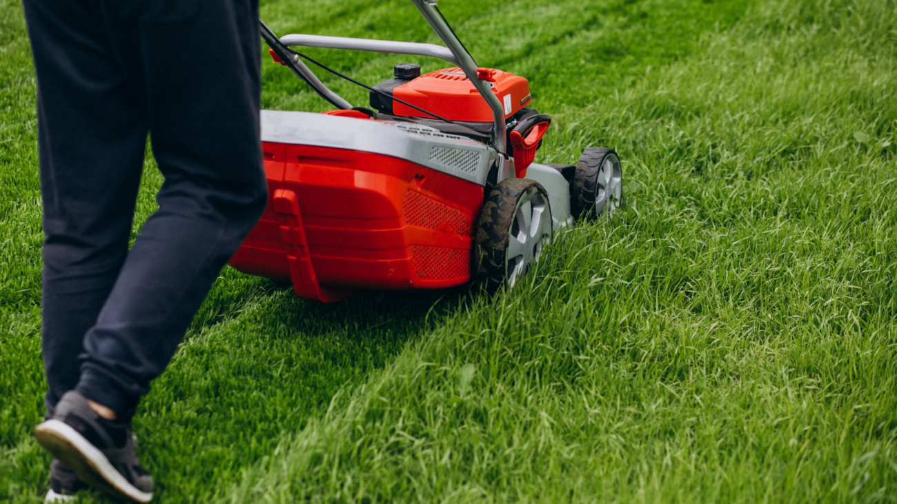 Man cutting grass with lawn mover in the back yard